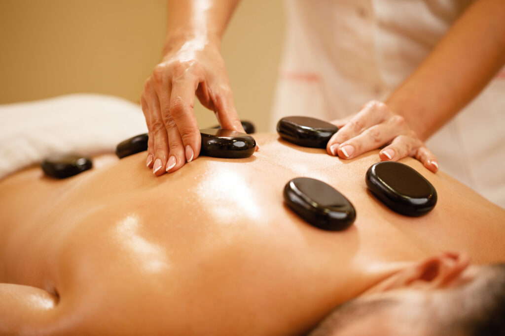 close up of man having hot stone therapy at the spa.